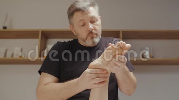男性脊医做骨科足部按摩在温泉沙龙的年轻女子视频的预览图