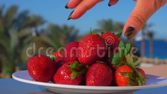手从盘子里取出一大块多汁的草莓视频的预览图