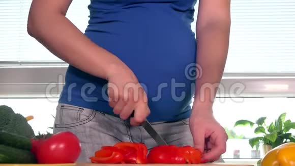 怀孕的妻子切了辣椒水果在厨房里微笑着看着摄像机视频的预览图