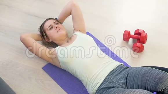 在家健身垫上运动的年轻疲惫女子的慢动作镜头视频的预览图