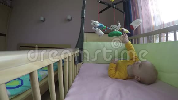 可爱的宝宝在床上玩旋转木马在肚子上翻滚4K视频的预览图
