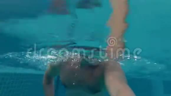 在游泳池里戴着橙色眼镜的活泼的年轻人假期暑期时间操作摄像机视频的预览图