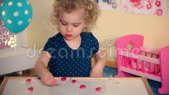 儿童从纸上取出糖果糖果用舌头在桌子上品尝视频的预览图