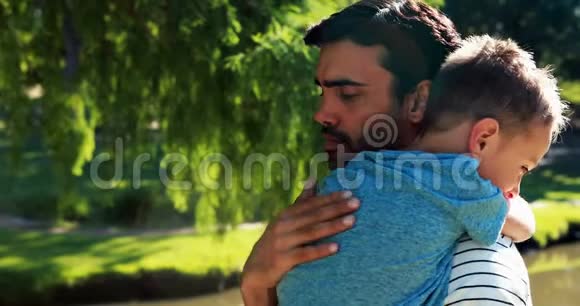 父亲抱着他睡着的儿子在公园视频的预览图