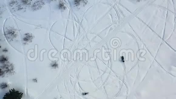 乘坐雪地摩托的俯视图录像两辆雪地摩托在雪地上留下脚印的顶部景色视频的预览图