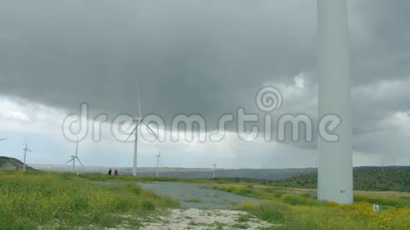 巨大的风力涡轮机叶片在灰色的雨天风暴垂直全景下旋转视频的预览图