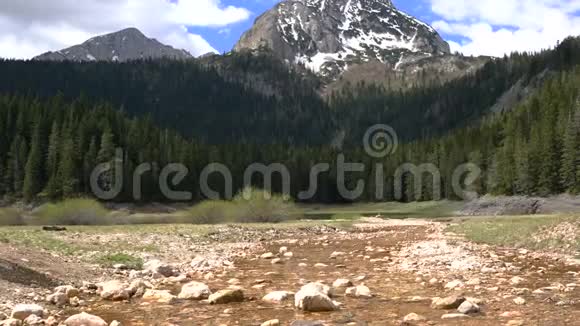 一个背包旅行者穿过一条小溪踩在石头上视频的预览图