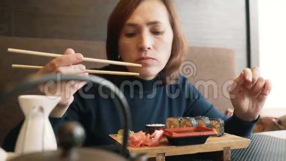女人在吃寿司那女孩正在用棍子吃面包卷视频的预览图