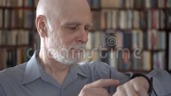 现代老人在家使用智能手表浏览阅读背景书架视频的预览图