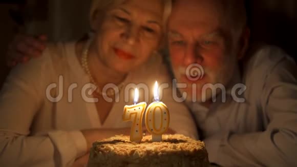 爱的老夫妇庆祝70周年与蛋糕在家里晚上吹灭蜡烛视频的预览图