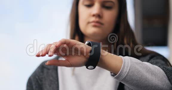 年轻的女人在街上用他的智能手表风吹拂着她的头发智能手表苹果时间4k视频的预览图