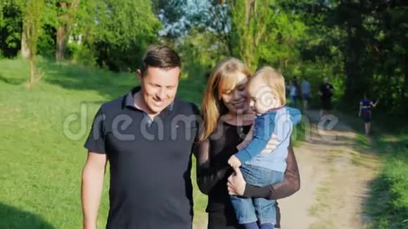一个年轻的高加索家庭正在公园里和一个小儿子散步宝贝抱着妈妈视频的预览图