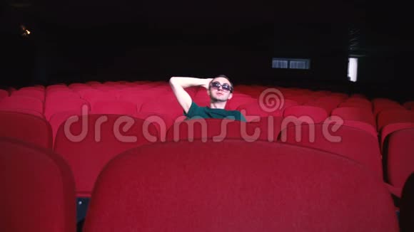 一个人坐在黑色电影院舒适的红椅子上笑着鼓掌视频的预览图