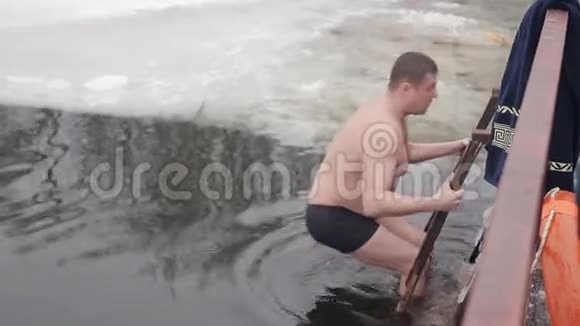 一个年轻人潜入冰冷的河水中民间传统健康的生活方式冬季结冰视频的预览图