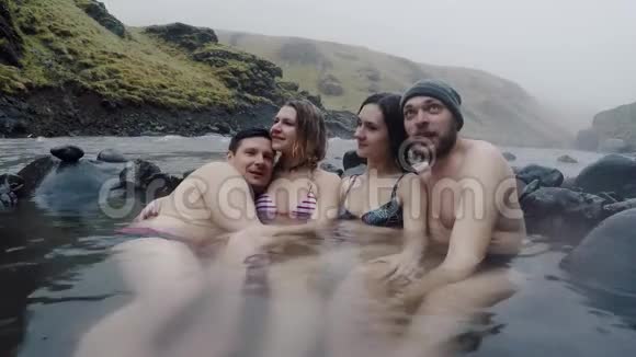 一群年轻人在冰岛山区的温泉上放松游客享受天然温泉视频的预览图