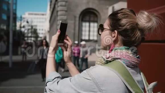 年轻时尚的女人站在街上为建筑物拍照女性使用智能手机拍照视频的预览图