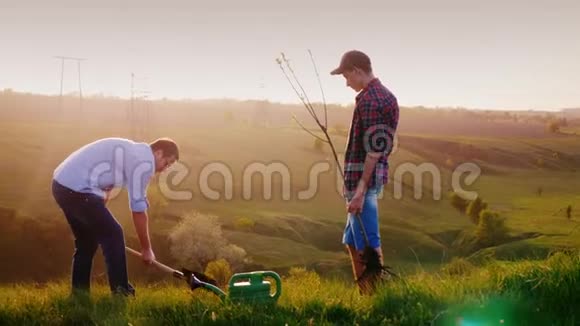 一个父亲和他的儿子一个青少年一起种一棵树图片背景视频的预览图