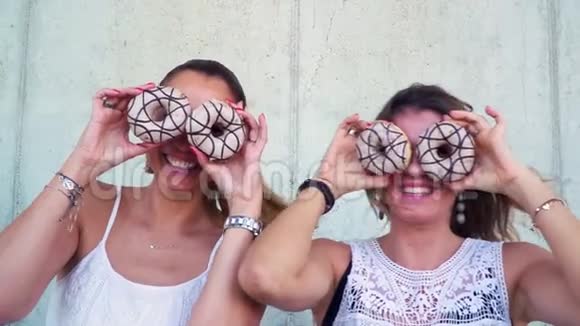 两个漂亮的女朋友在一起玩得很开心玩甜甜圈视频的预览图