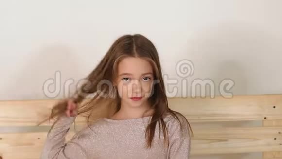 可爱的小女孩坐在时尚工作室的长凳上为相机摆姿势视频的预览图