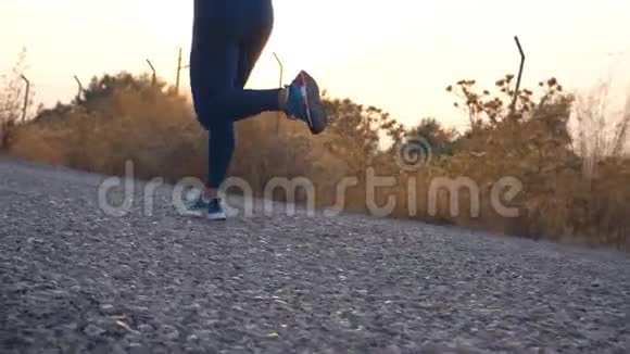 跟着年轻女孩在乡间小路上奔跑的脚女腿在大自然中慢跑活跃的生活方式慢动作视频的预览图