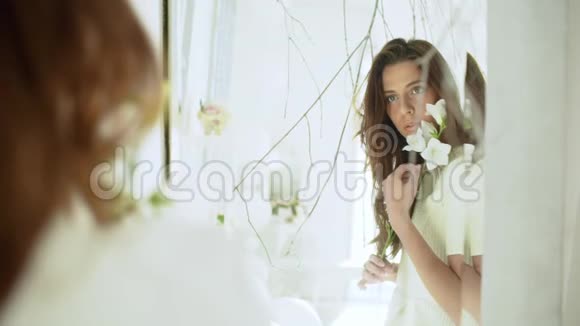 年轻漂亮的女孩穿着白色的装饰照镜子慢动作视频的预览图