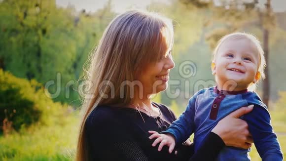 快乐的母亲和她的小儿子在镜头里微笑户外肖像视频的预览图