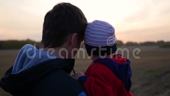 年轻的父亲手牵着孩子看日落温柔和怀抱的挚爱父亲室外视频的预览图