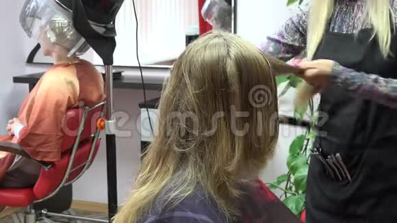 发型师在吹风机机下设置发型和其他女人4K视频的预览图
