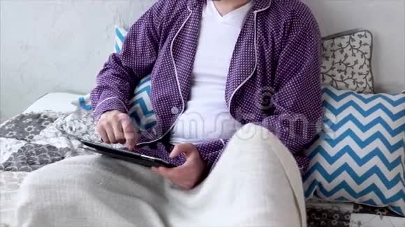 近距离拍摄一个男人手他在卧室里用便携式平板电脑工作视频的预览图