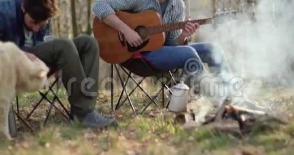 男人弹吉他朋友一起在火的地方抚摸狗真正的朋友户外露营帐篷度假视频的预览图