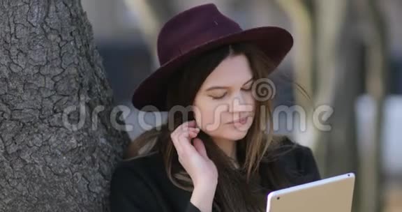 漂亮的微笑时髦女孩在公园里放松和使用平板电脑4kStealam视频的预览图