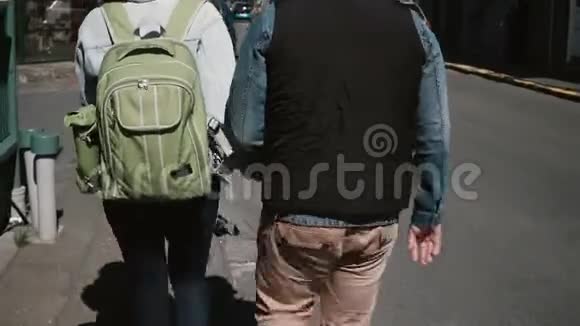 在阳光明媚的日子里年轻时尚的夫妇在街上散步男人和女人牵着手视频的预览图