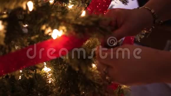 节日前后女人在圣诞树上系蝴蝶结视频的预览图