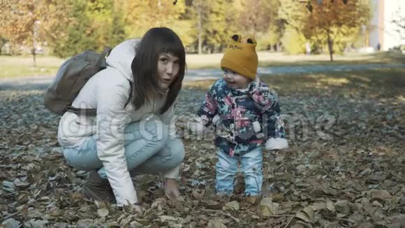 快乐的母女俩一起玩秋叶一起玩得开心嬉戏的女孩和她的母亲扔树叶视频的预览图