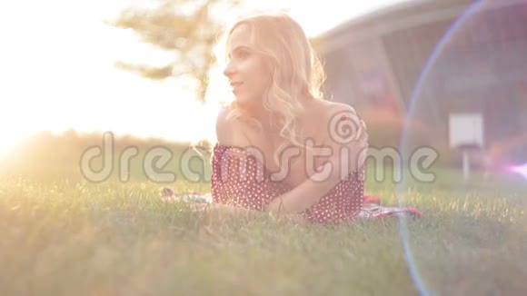 年轻的美女躺在公园的草地上视频的预览图