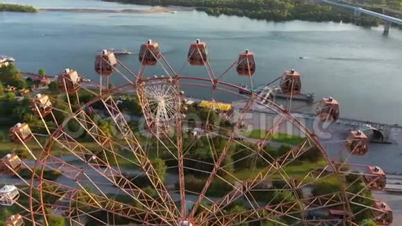 在河和城市景观上无人机可以看到游乐园里五颜六色的摩天轮大型摩天轮游乐园视频的预览图