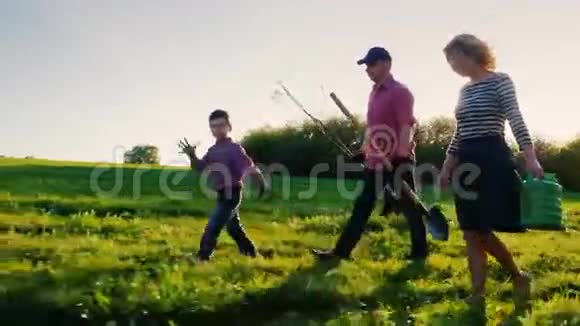 侧观一家农民带着一个小儿子一起去植树承担苹果树苗铲子和视频的预览图