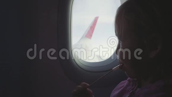 小女孩在飞机上用木棍在舷窗上吮吸糖果视频的预览图
