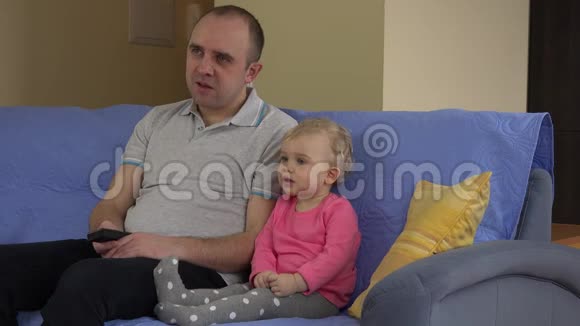 爸爸看电视小可爱的女孩坐在沙发上4K视频的预览图