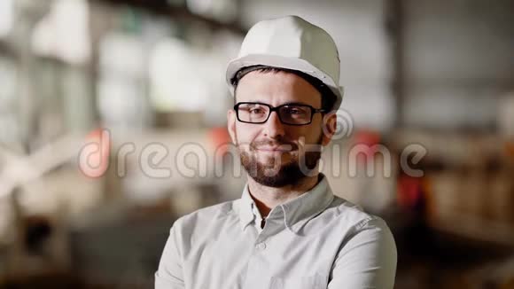 在施工区域内将留着胡须的人穿着白色衬衫戴着防护头盔和眼镜年轻建筑师视频的预览图