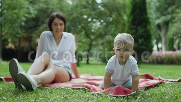 妈妈和儿子坐在公园的格子呢上视频的预览图