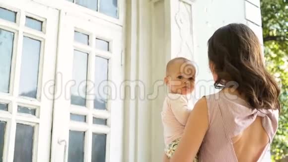 美丽的妈妈拥抱着亲吻着后院里欢快的婴儿视频的预览图