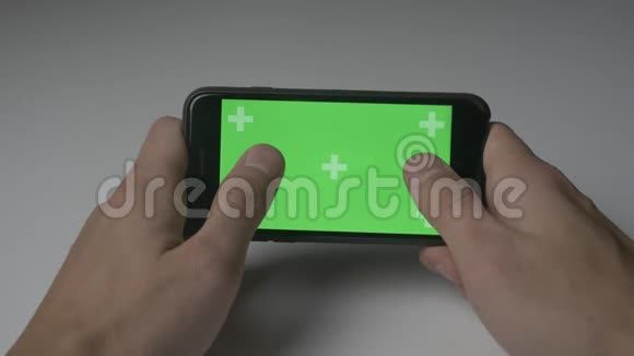 近距离男子玩游戏与智能手机绿色屏幕色度键在白色桌面背景视频的预览图
