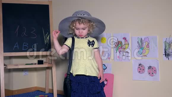 可爱的小模特女孩带着帽子和手提包展示时尚视频的预览图