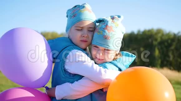 两个双胞胎姐妹拥抱亲吻孩子们拿着气球视频的预览图