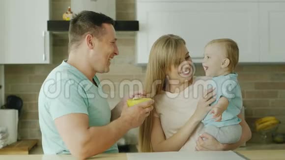 一对恩爱的父母用勺子喂孩子和他玩逗他开心幸福的家庭健康的饮食视频的预览图
