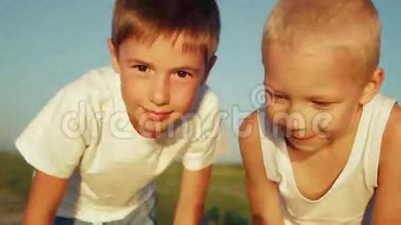 两个穿着白色衣服的男孩在公园里看着视频的预览图