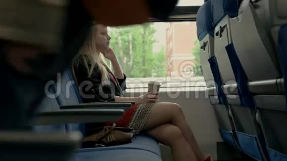 年轻漂亮的女人坐在火车上在火车上喝咖啡的女孩视频的预览图