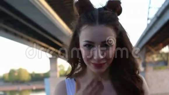 美丽的女模特在桥的背景上长着长长的黑发吹着吻视频的预览图