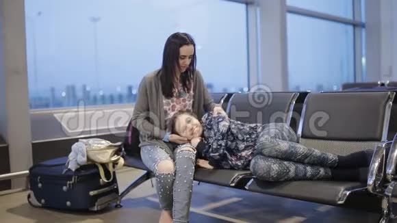 一个女人和她的女儿在候机室机场过夜等待航班视频的预览图